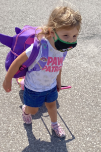 Small child walking with backpack and small suitcase