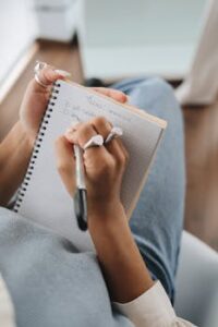 A detailed close-up of a hand with rings writing in a spiral notebook, perfect for educational themes.
