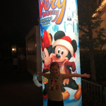Child standing at entrance of Mickey's Very Merry Christmas Party Sign.