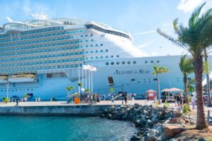 Discover the majestic Allure of the Seas docked in a vibrant tropical port.