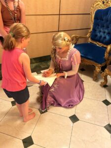 Child getting autograph from Rapunzel.